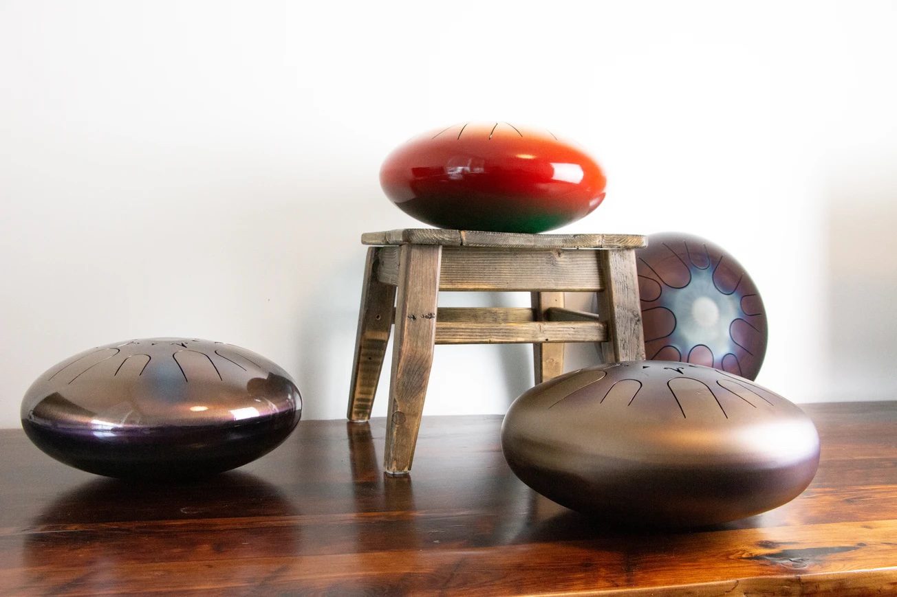 Artisan Instruments Red Singing Steel Drum on Stool More Drums on Wood Floor